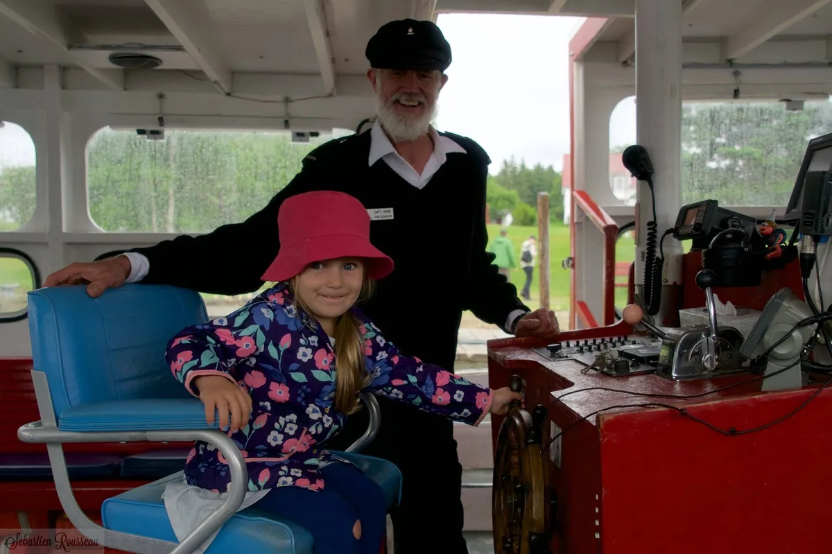 Captain Vince showing a little girl how to drive the Puffin Express boat in 2016