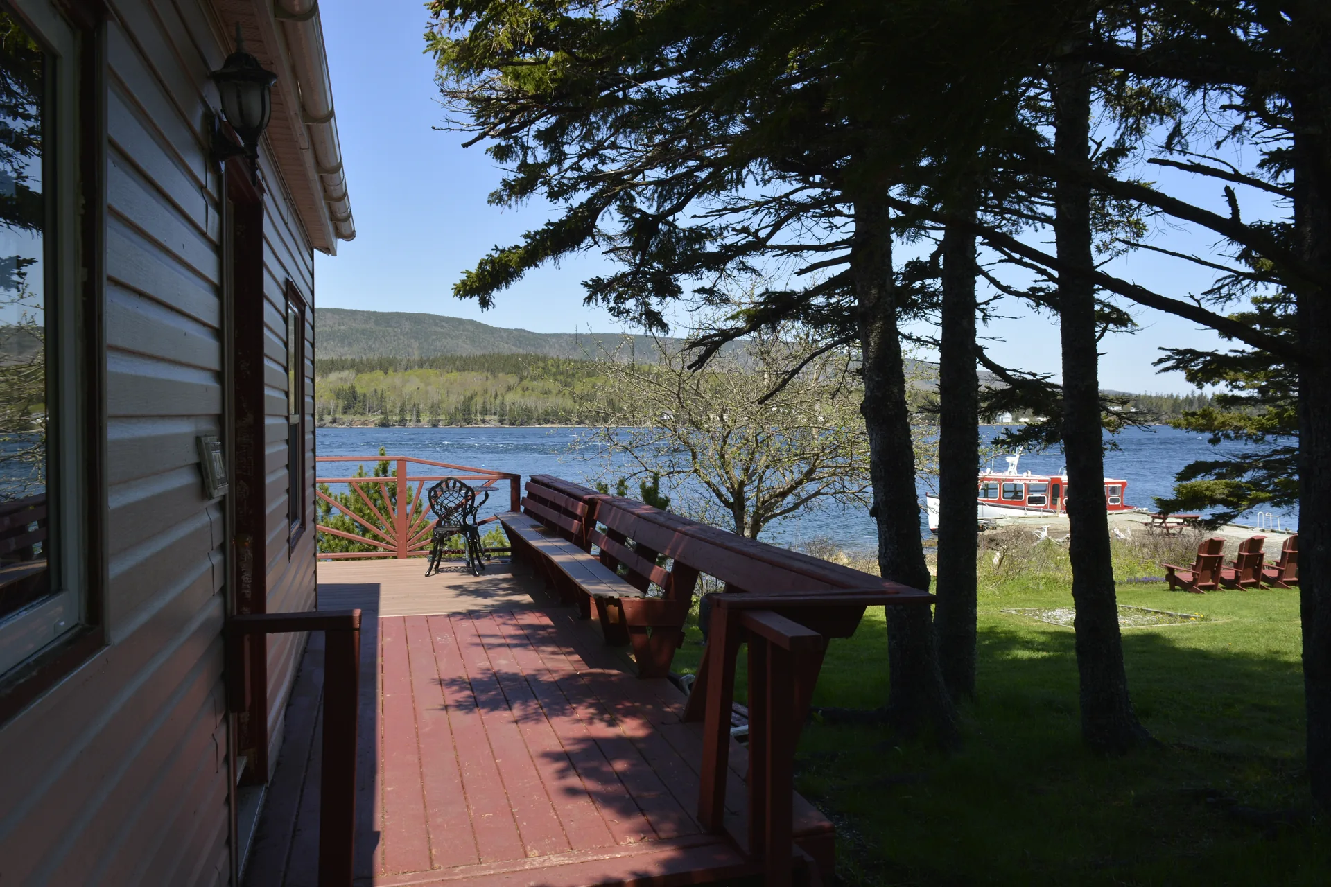Cottage deck with ocean view visible and boat in the background